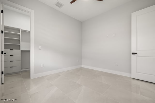 unfurnished bedroom featuring light tile patterned flooring, ceiling fan, a closet, and a walk in closet