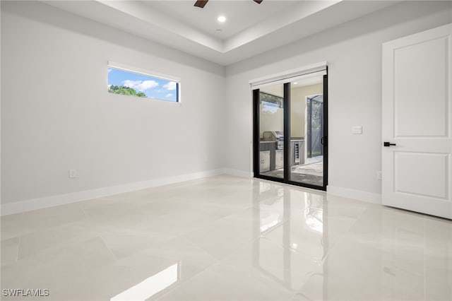 spare room with light tile patterned flooring, ceiling fan, and a tray ceiling