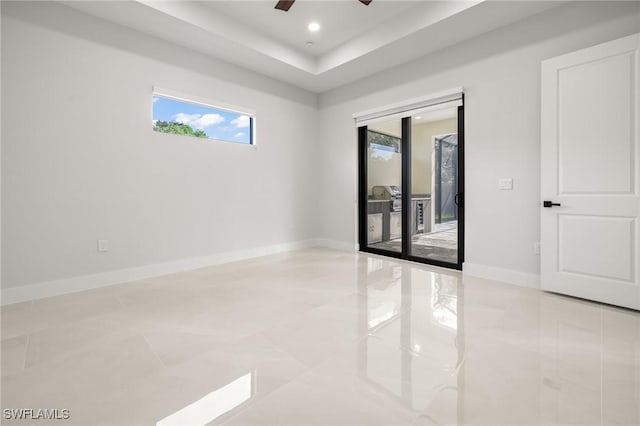 728 SW 8th Ter, Cape Coral, FL 33991 - tiled spare room with a ceiling fan, a tray ceiling, and baseboards