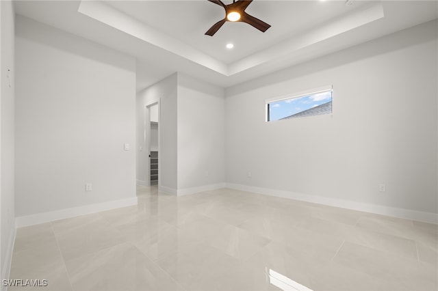 tiled spare room with a tray ceiling and ceiling fan