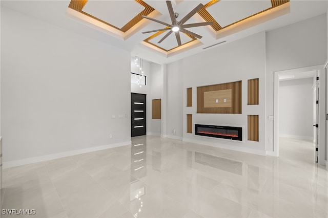 tiled living room with coffered ceiling, ceiling fan, and a towering ceiling