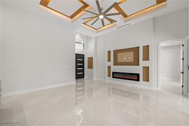 728 SW 8th Ter, Cape Coral, FL 33991 - unfurnished living room featuring a glass covered fireplace, a ceiling fan, light tile patterned flooring, baseboards, and a towering ceiling