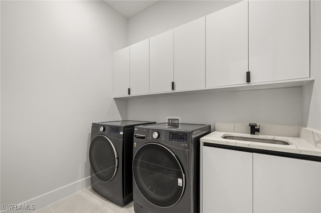 laundry room with light tile patterned flooring, cabinets, sink, and separate washer and dryer