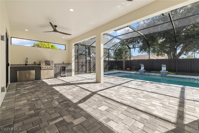 view of pool featuring glass enclosure, a patio area, grilling area, sink, and ceiling fan