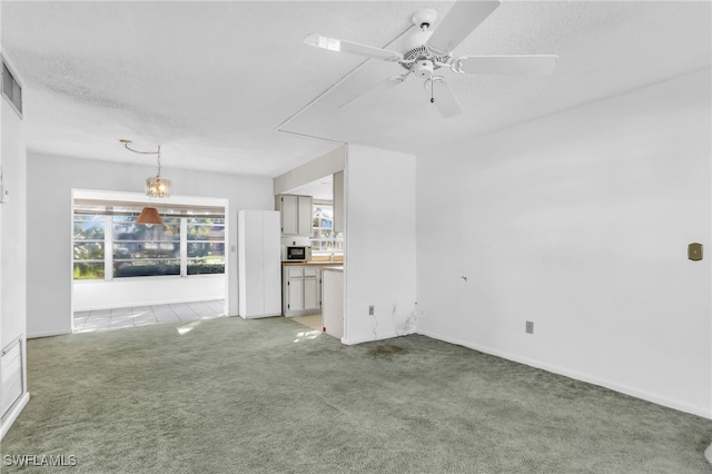 unfurnished living room featuring carpet flooring, ceiling fan, and a textured ceiling