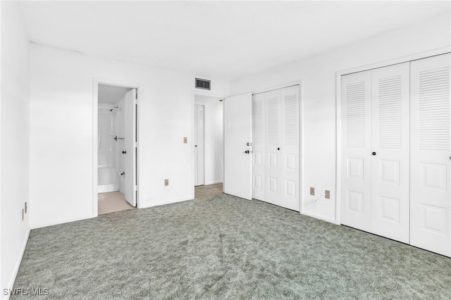 unfurnished bedroom with two closets, carpet floors, and ensuite bathroom