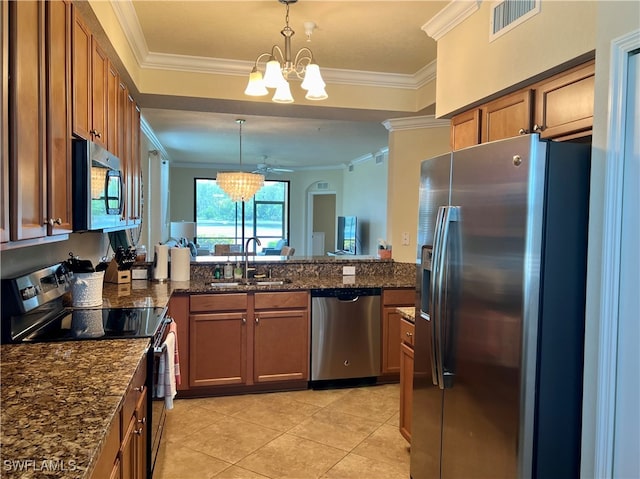 kitchen featuring ornamental molding, appliances with stainless steel finishes, pendant lighting, sink, and dark stone countertops