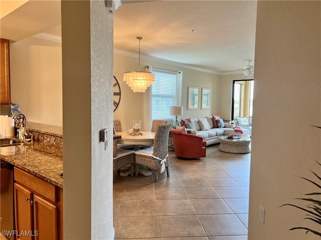 living room with light tile patterned flooring, sink, ornamental molding, and ceiling fan with notable chandelier