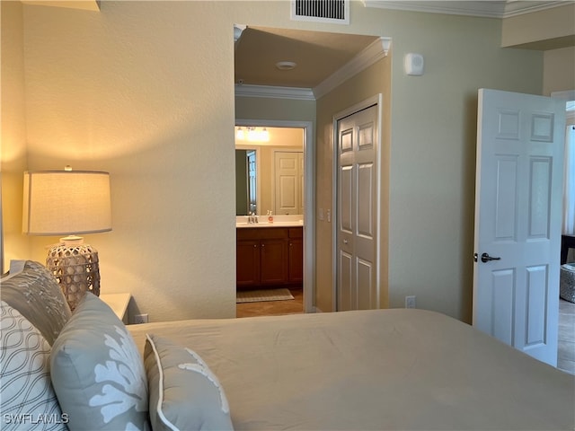 bedroom with a closet, ornamental molding, and ensuite bathroom