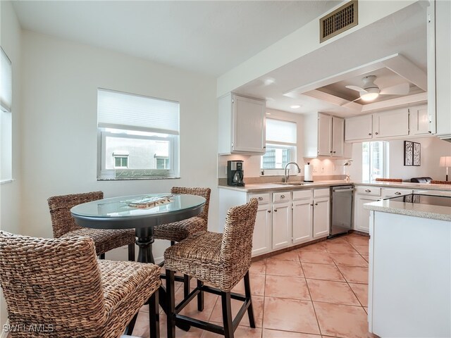 kitchen featuring ceiling fan, dishwasher, sink, a tray ceiling, and white cabinets