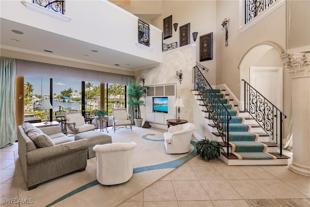 tiled living room with decorative columns, a high ceiling, and ornamental molding