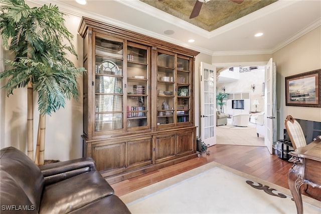 office space with ornamental molding, ceiling fan, a tray ceiling, hardwood / wood-style floors, and french doors