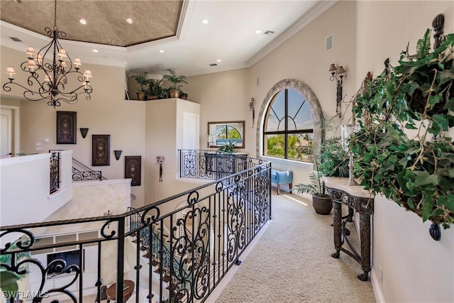 corridor with a high ceiling, a chandelier, carpet flooring, and crown molding