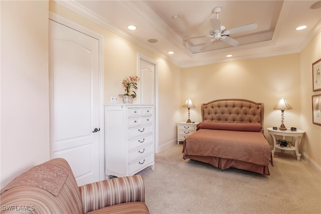 bedroom with a tray ceiling, light colored carpet, ceiling fan, and crown molding