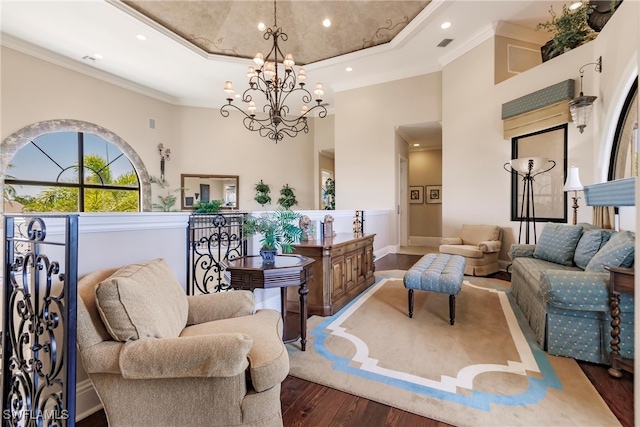 living room with ornamental molding, a raised ceiling, dark hardwood / wood-style flooring, a high ceiling, and a chandelier