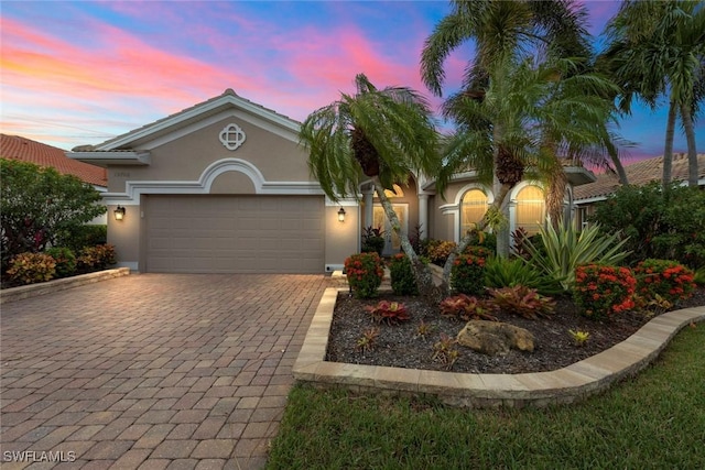 view of front of property featuring a garage, decorative driveway, and stucco siding