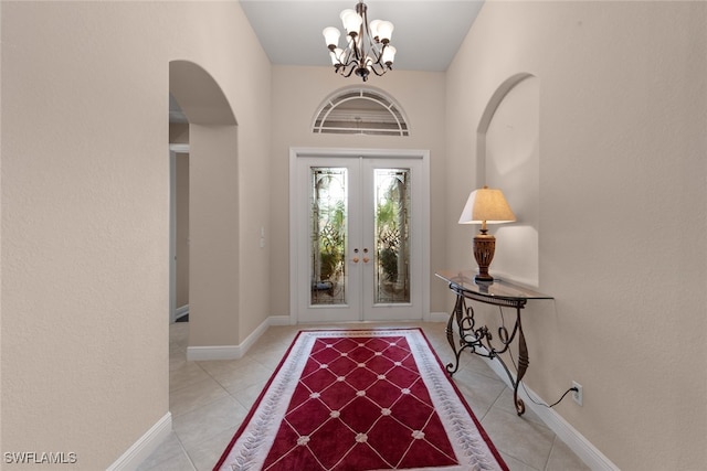 tiled foyer featuring a chandelier and french doors