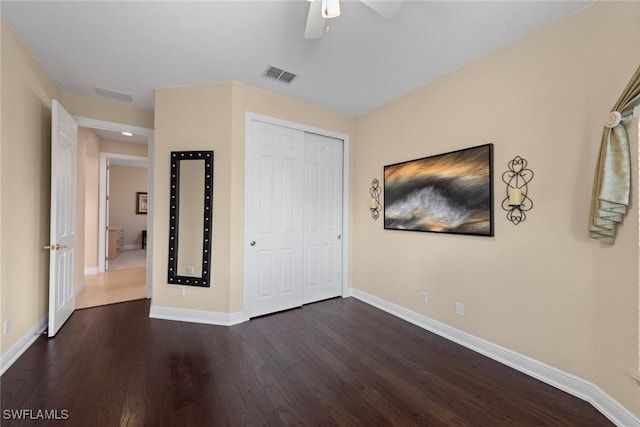 unfurnished bedroom featuring baseboards, a closet, visible vents, and dark wood-style flooring