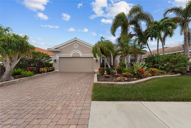 view of front facade with a garage, decorative driveway, and stucco siding