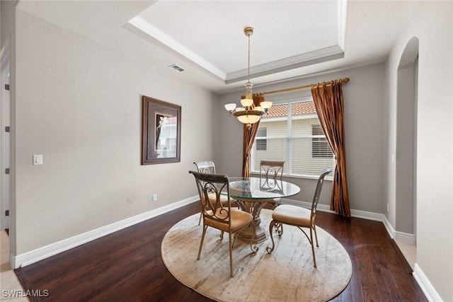 dining area with wood finished floors, a raised ceiling, visible vents, and baseboards