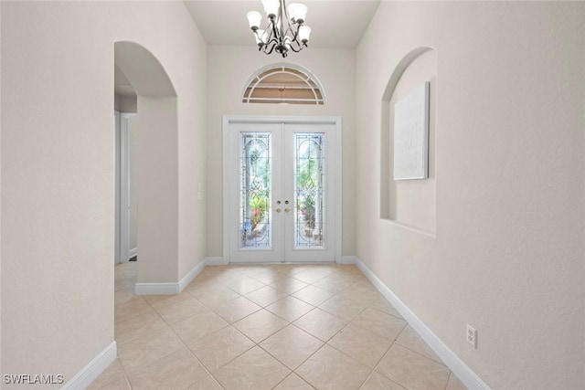 foyer featuring a chandelier, french doors, light tile patterned floors, and baseboards