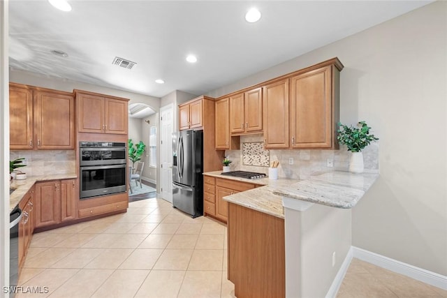 kitchen featuring light tile patterned floors, visible vents, appliances with stainless steel finishes, light stone counters, and a peninsula