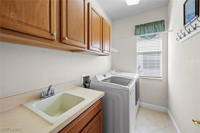 washroom featuring light tile patterned floors, cabinet space, a sink, washer and dryer, and baseboards