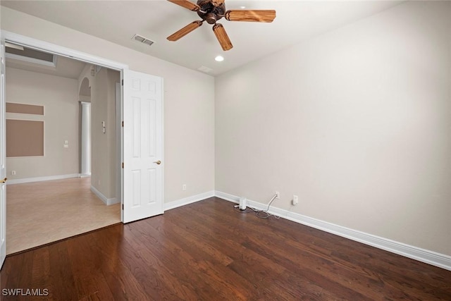 empty room with baseboards, visible vents, arched walkways, dark wood finished floors, and ceiling fan