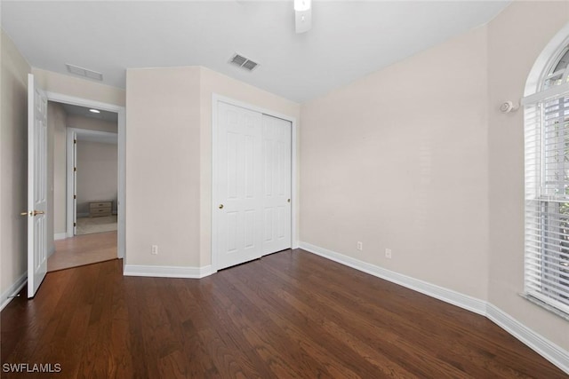 unfurnished bedroom with a closet, visible vents, baseboards, and wood finished floors