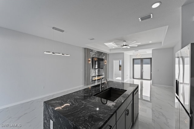 kitchen with a tray ceiling, sink, dark stone counters, and french doors