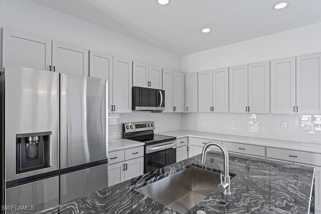 kitchen featuring dark stone counters, tasteful backsplash, sink, and stainless steel appliances