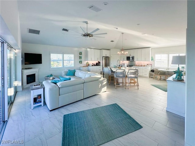 living room with ceiling fan with notable chandelier and lofted ceiling