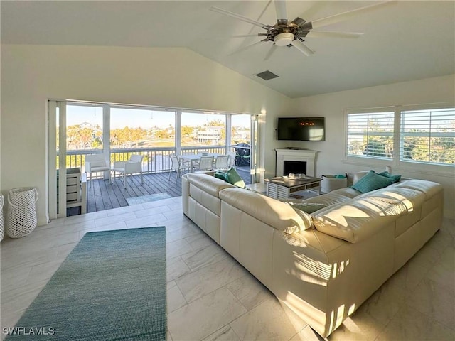 living room with a wealth of natural light, ceiling fan, and vaulted ceiling