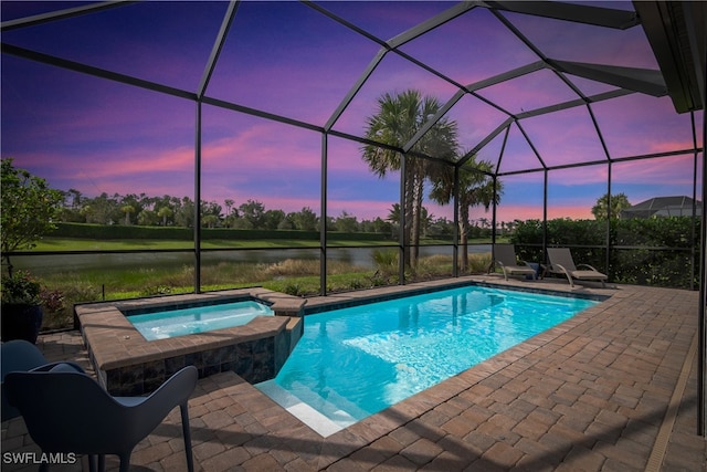 pool at dusk featuring a lanai, a water view, an in ground hot tub, and a patio