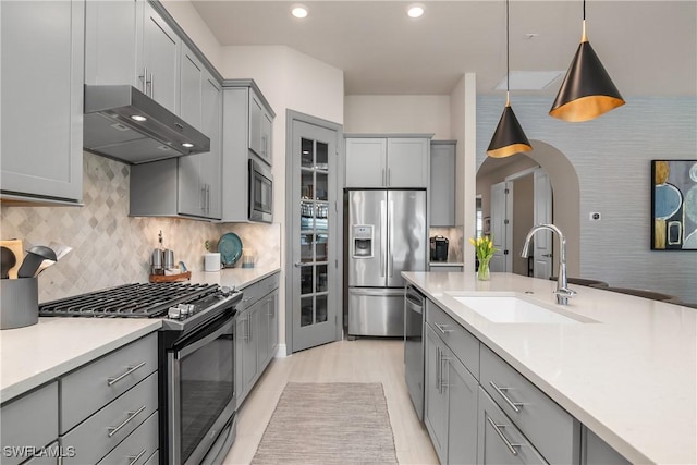 kitchen with gray cabinetry, sink, stainless steel appliances, decorative light fixtures, and decorative backsplash