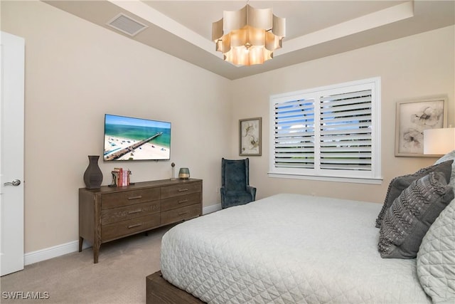 carpeted bedroom with a notable chandelier and a raised ceiling