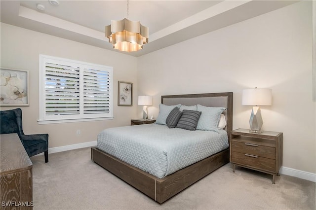 bedroom featuring a tray ceiling, an inviting chandelier, and light colored carpet