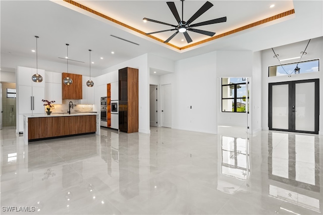 kitchen featuring french doors, a center island, decorative light fixtures, and a tray ceiling