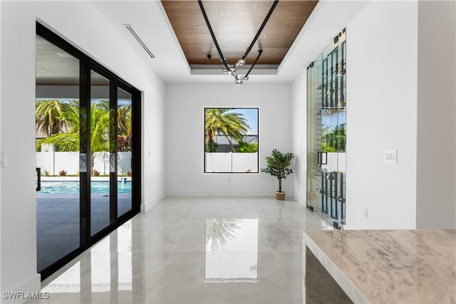 doorway to outside featuring a raised ceiling and wood ceiling