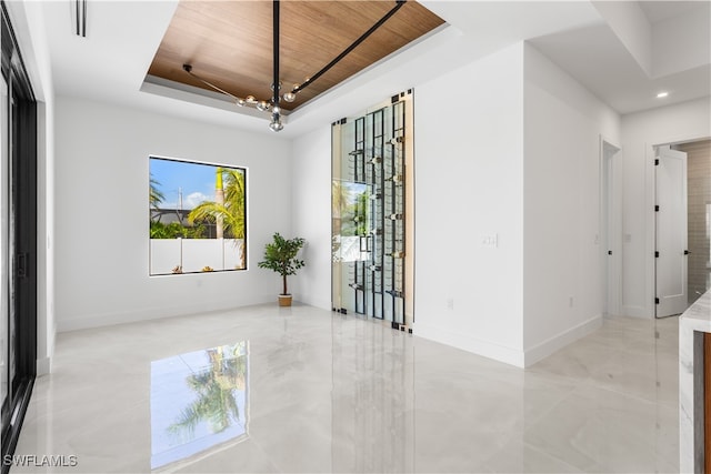 empty room with a tray ceiling and wood ceiling