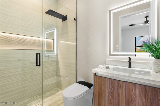 bathroom with vanity, toilet, ceiling fan, and a shower with door