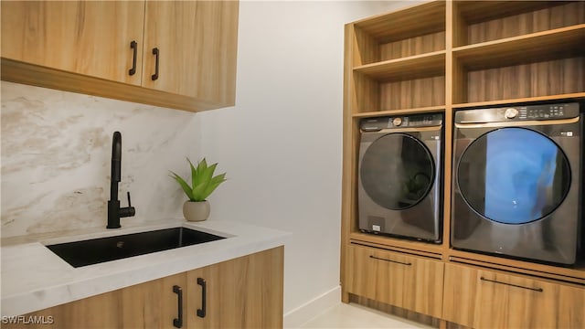 laundry area featuring washing machine and clothes dryer, sink, and cabinets