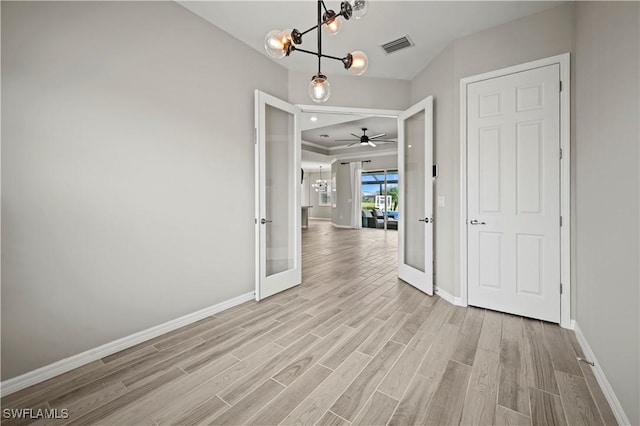 interior space with french doors, ceiling fan with notable chandelier, and light hardwood / wood-style flooring