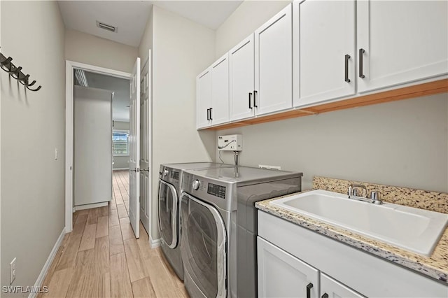 laundry room featuring washer and dryer, light hardwood / wood-style floors, cabinets, and sink