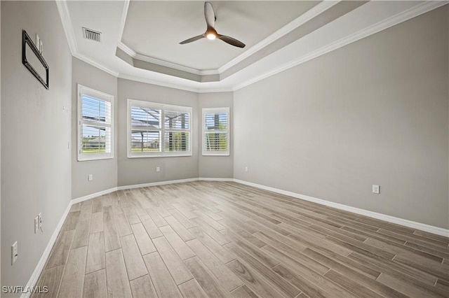 empty room featuring ceiling fan, light hardwood / wood-style floors, ornamental molding, and a tray ceiling