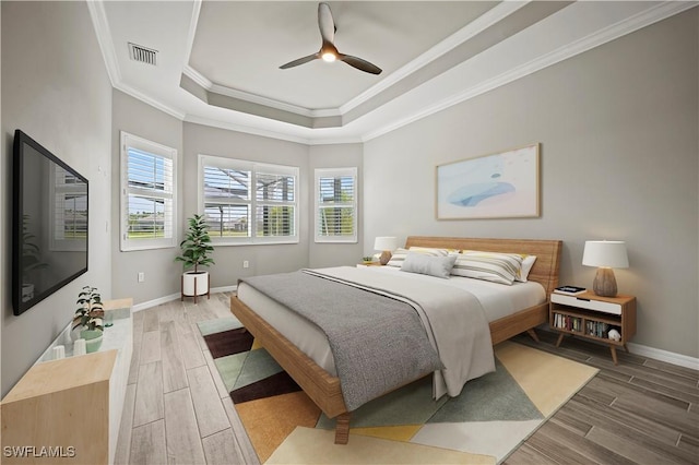 bedroom featuring a raised ceiling, multiple windows, ceiling fan, and ornamental molding