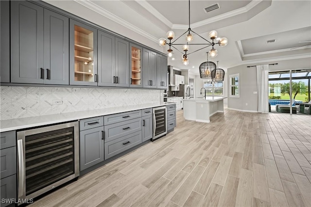 kitchen featuring pendant lighting, backsplash, wine cooler, and a tray ceiling