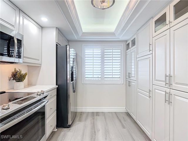 kitchen featuring a raised ceiling, white cabinets, light stone countertops, and stainless steel appliances