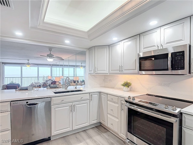 kitchen with white cabinets, stainless steel appliances, sink, backsplash, and a raised ceiling