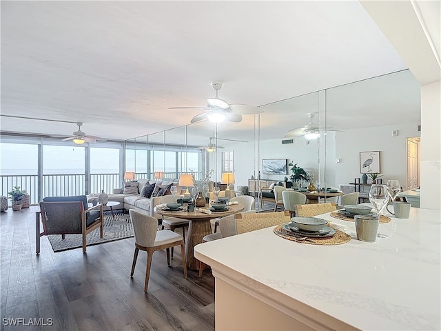 dining area with a water view, expansive windows, and dark hardwood / wood-style flooring